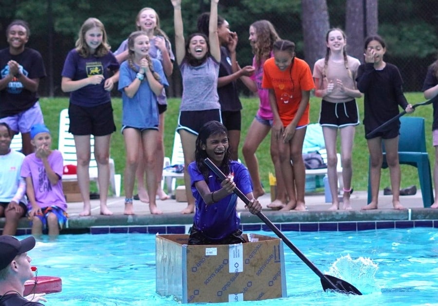 photo of female camper in cardboard boat in pool