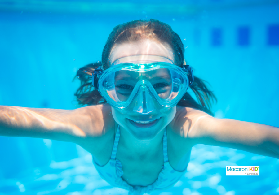 child swimming underwater in pool with goggles