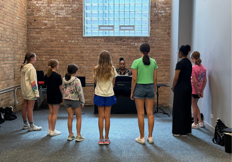 seven girls around a piano singing