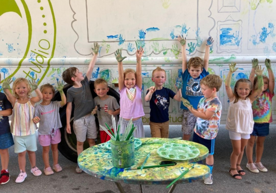Children standing outside of art truck with paint on their hands