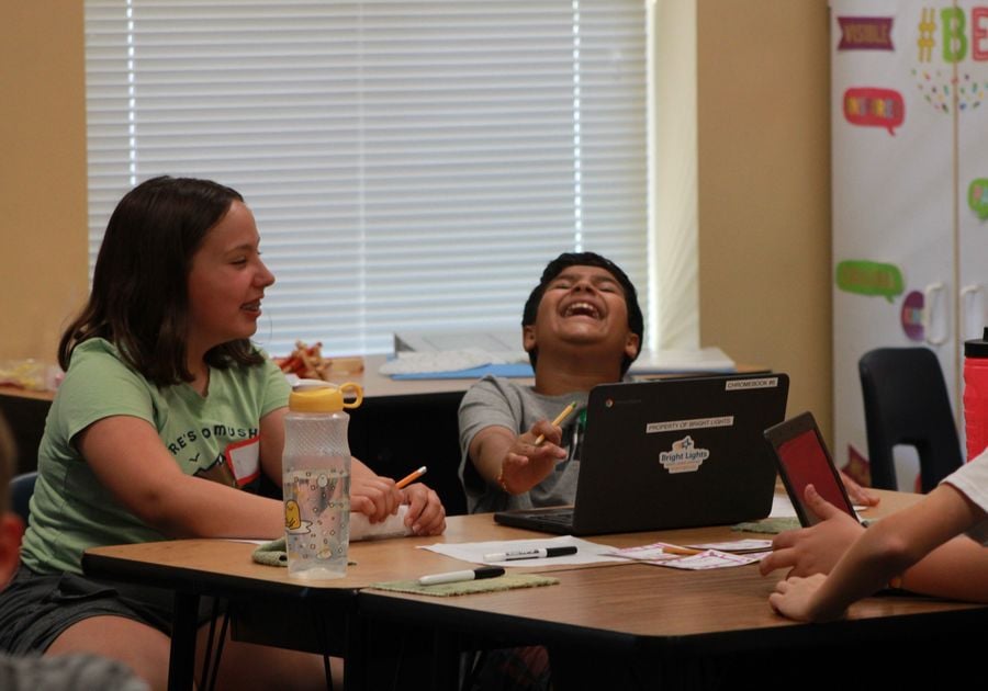 Two children laughing by a computer