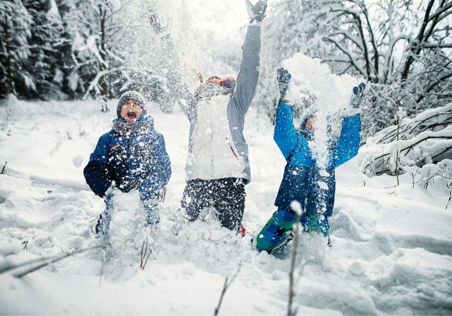 Happy kids throwing fresh powder snow into the air and yelling