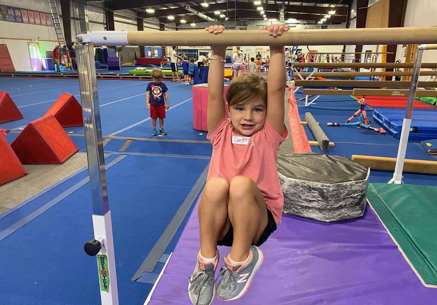 Young boy hanging from a gymnastics bar