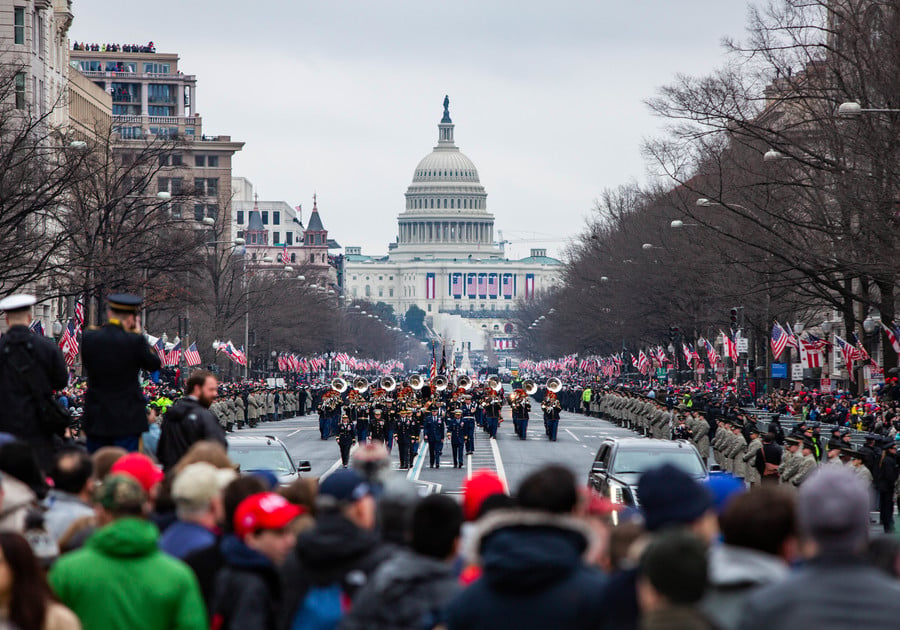 Inauguration Day at the United States Capitol 2017 showing a large crowd with the capitol at the end of the street, lots of American flags and a band playing in the street