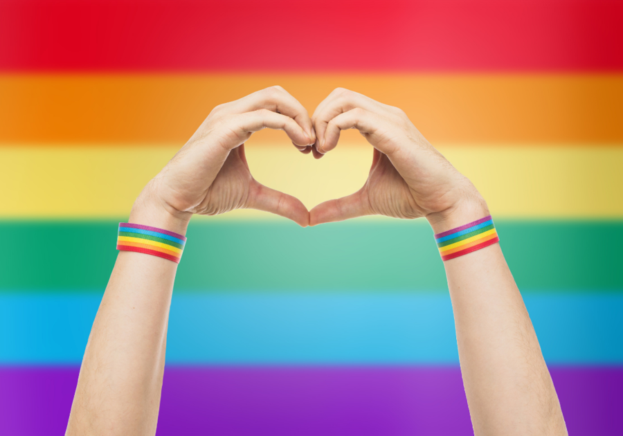 hands in a heart in front of a pride flag