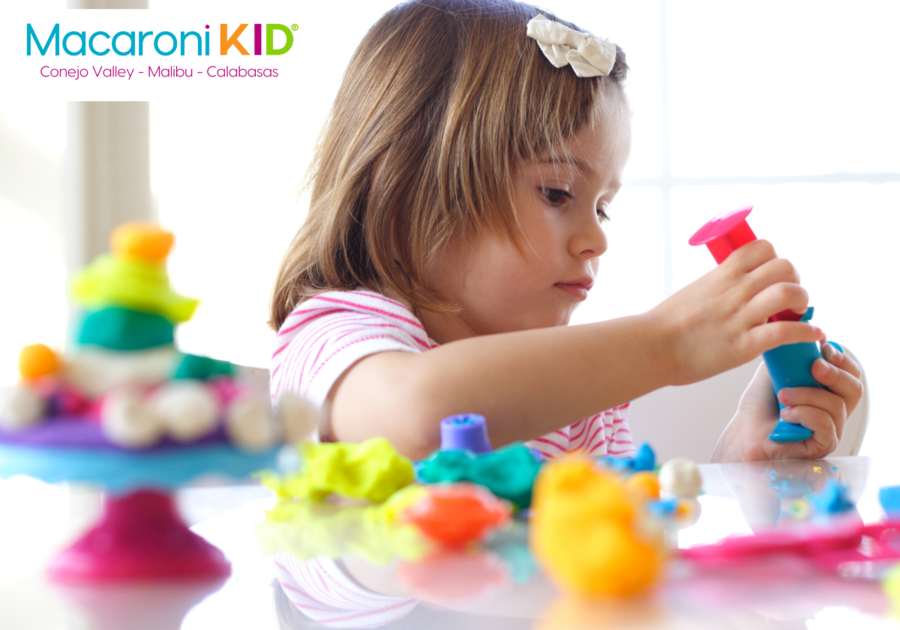 Little girl playing with colorful Play Doh