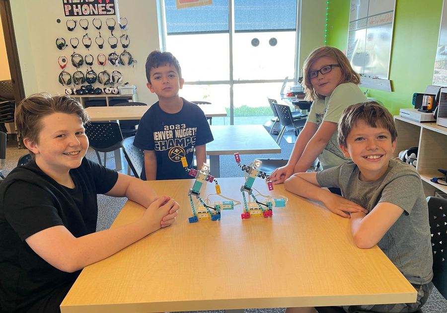 four smiling children building dancing robots at Code Ninjas Parker