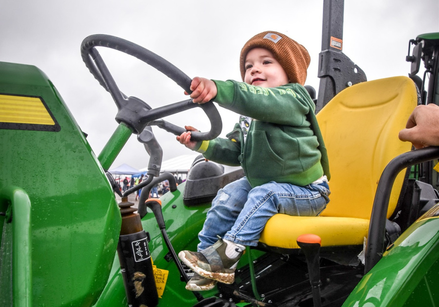 young child pretending to drive a real tractor