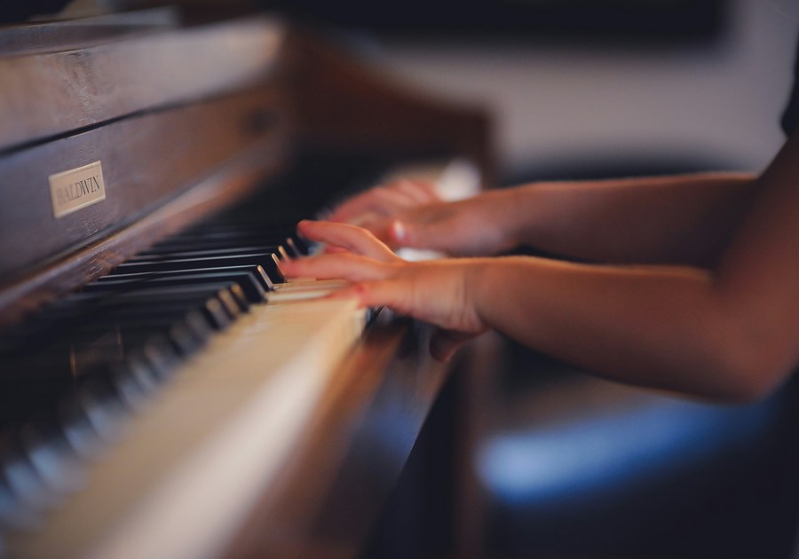 Tiny fingers on the keyboard. Kid playing piano