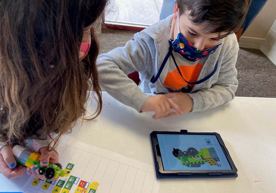 Children building with legos using instructions on an ipad
