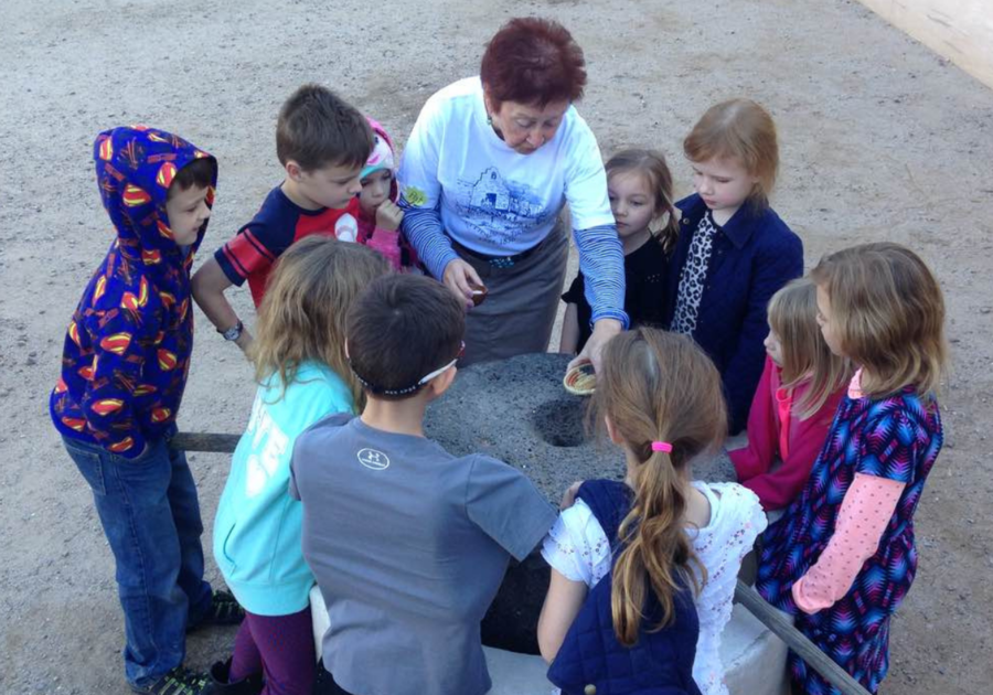 Children gathered around an historic cooking tool