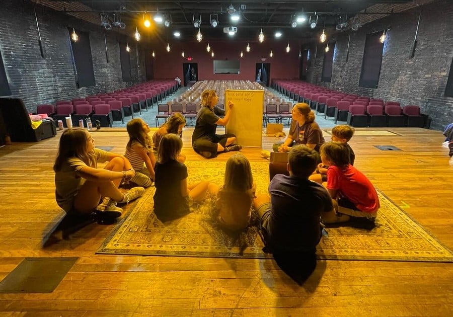 photo of campers seated on stage with teacher