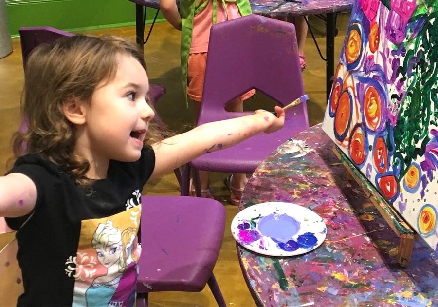 photo of young child painting on a canvas