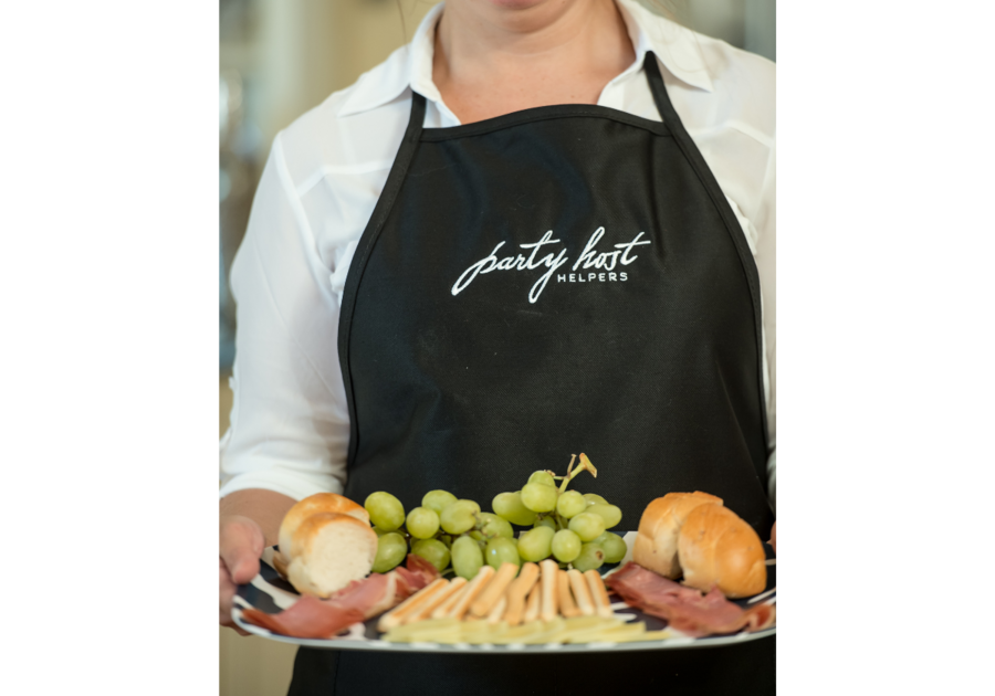 person in apron carrying a charcuterie tray