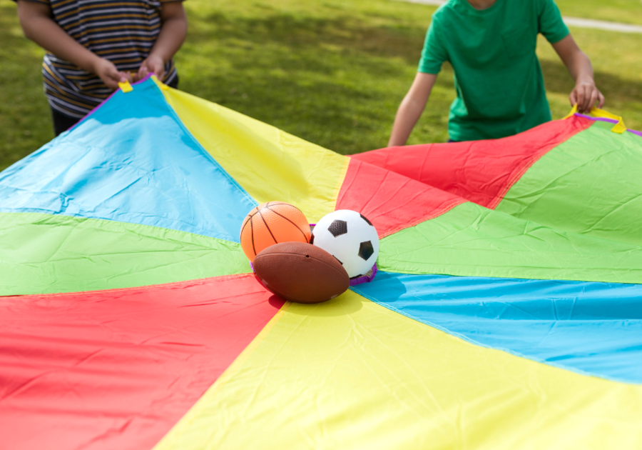 children holding parachute with sports balls in the middle