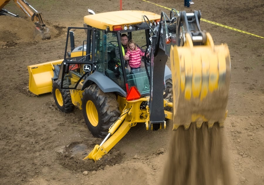 young child and adult operating heavy machinery together