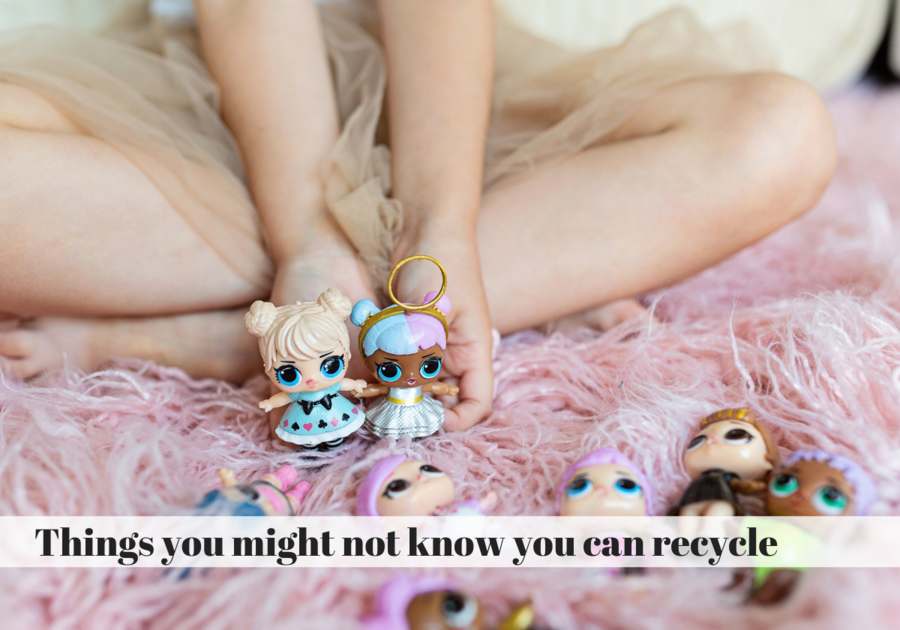 Child holding two LOL Surprise Dolls in hands and six over dolls lay in the carpet around them.