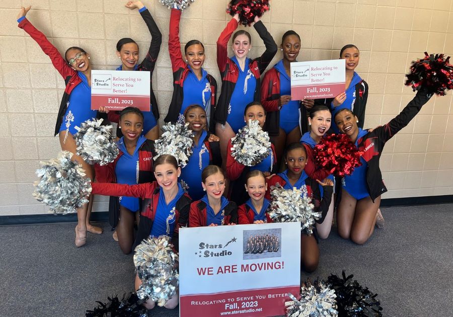 Dancers in Blue, Red & Black holding pom poms and signs with relocation information for new studio location