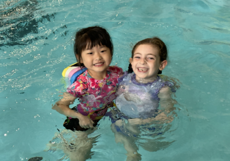 two smiling girsl in an indoor pool