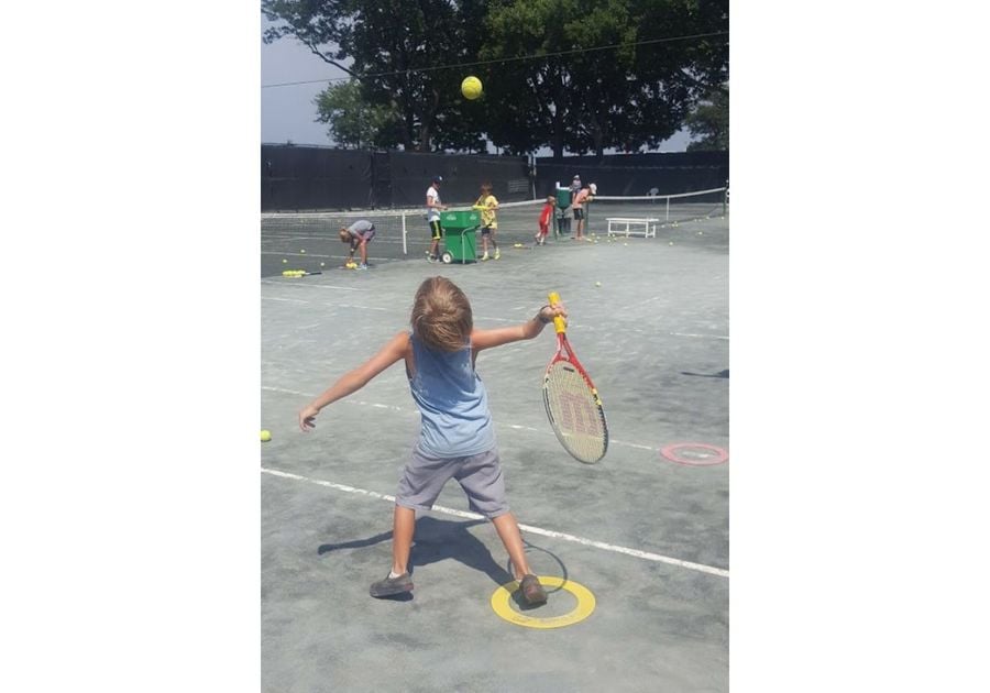 young boy serving a tennis ball