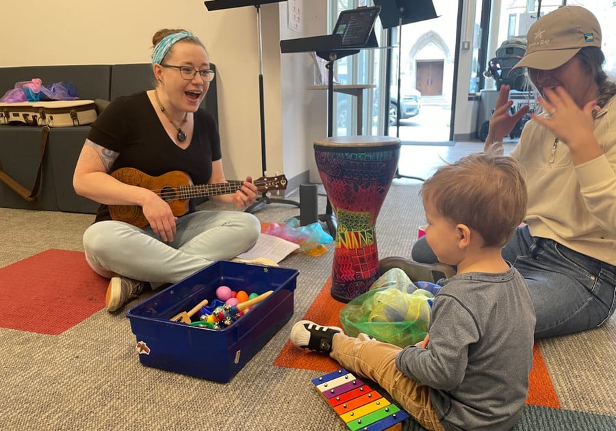 lady on the floor playing ukelele for a child