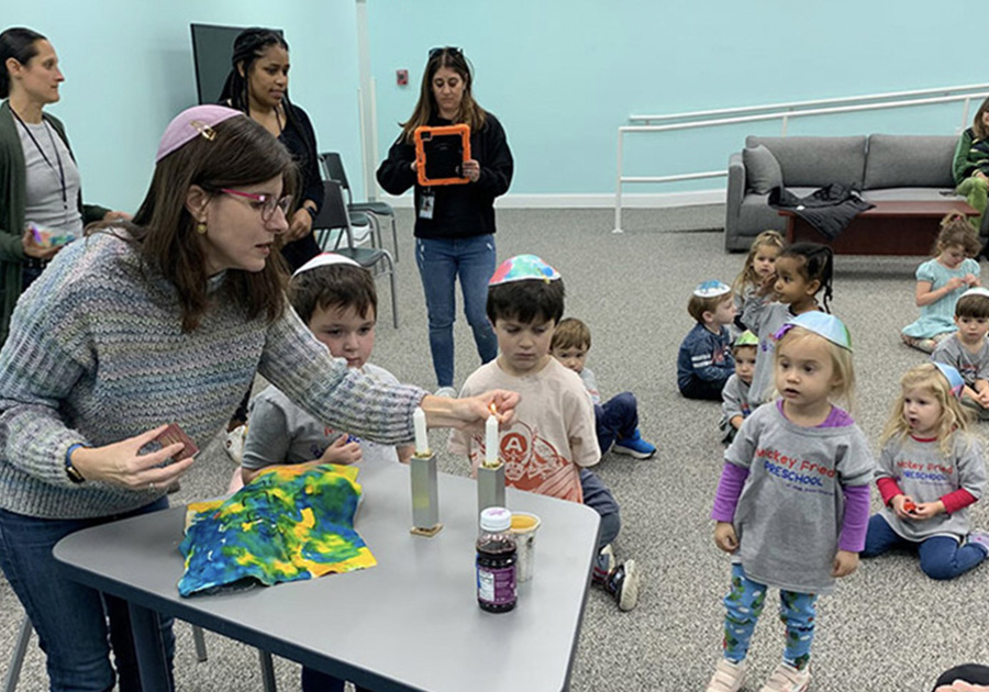 Kids watching a teacher demonstrating a preschool activity over a table