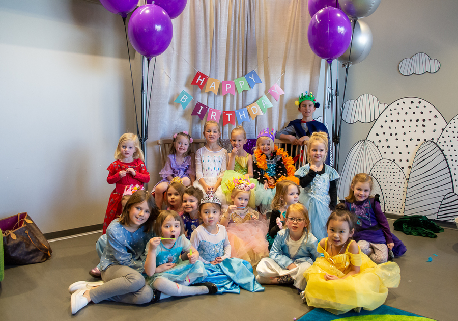 children posing for a group photo in front of a themed backdrop at a Douglas County Libraries birthday party