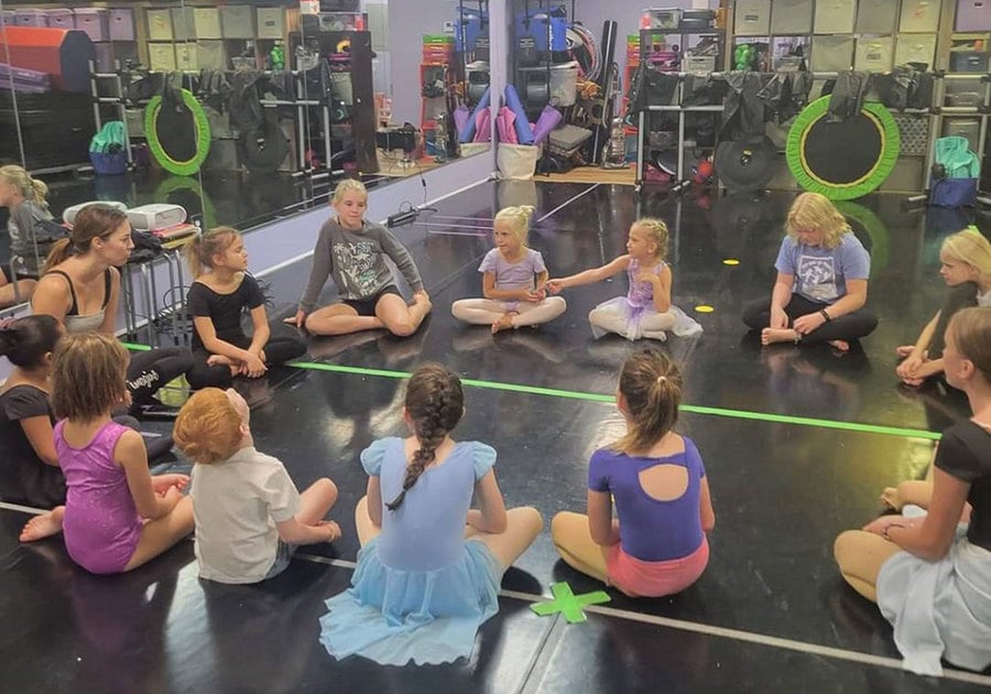 Dance students sitting in a circle on the floor