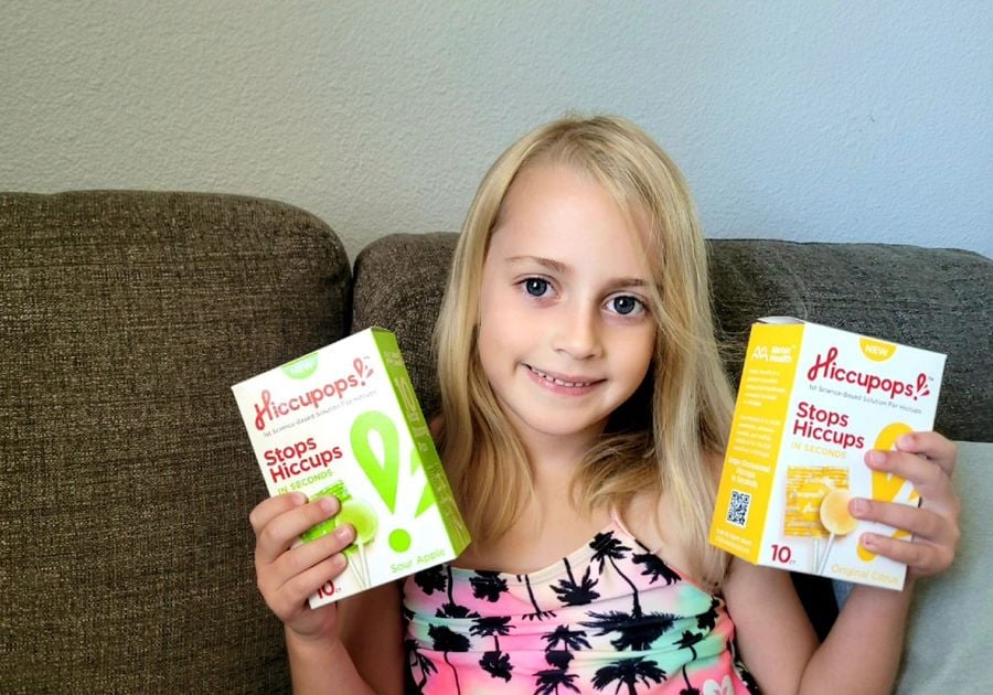 Little girl holding Hiccupops boxes and smiling.