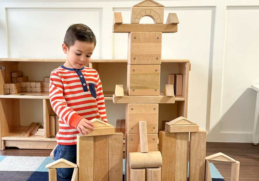 child building large wooden block tower at Play Street Museum
