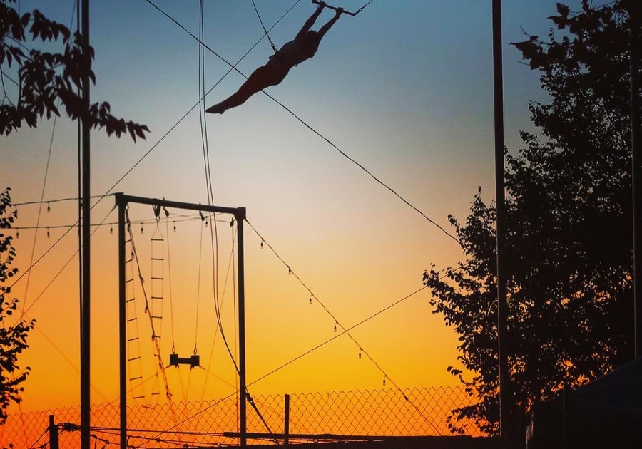 woman swinging on trapeze at sunset