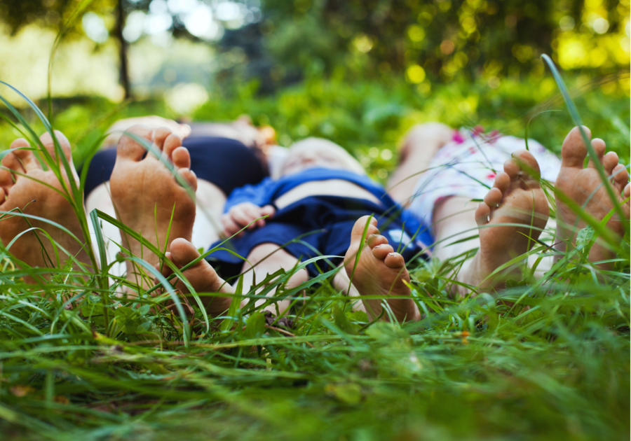 Family of three bare feet laying on the grass