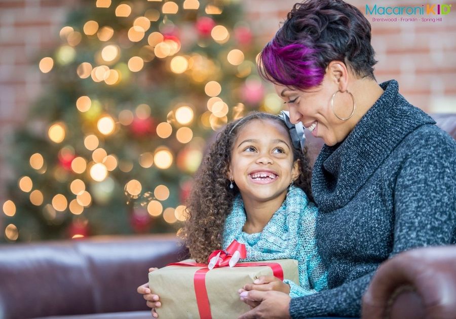 Little girl and mother on couch with Christmas tree in background