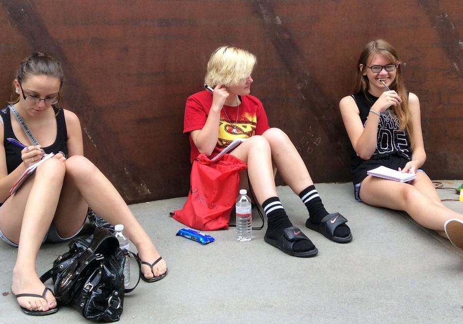 Three kids sitting against a wall