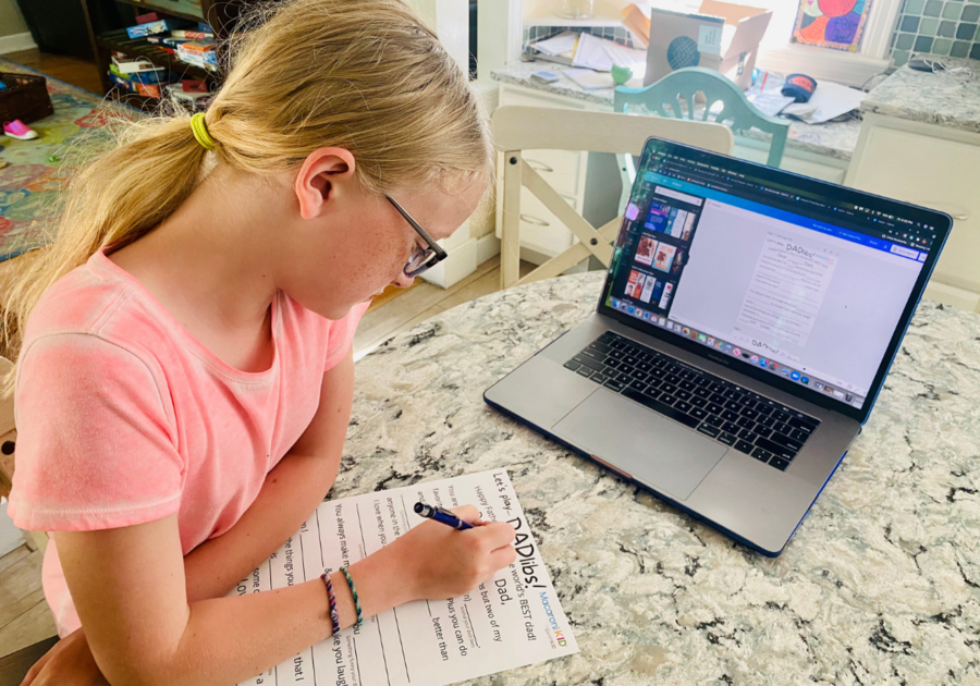 Little girl working on printable in front of a computer opened to Canva